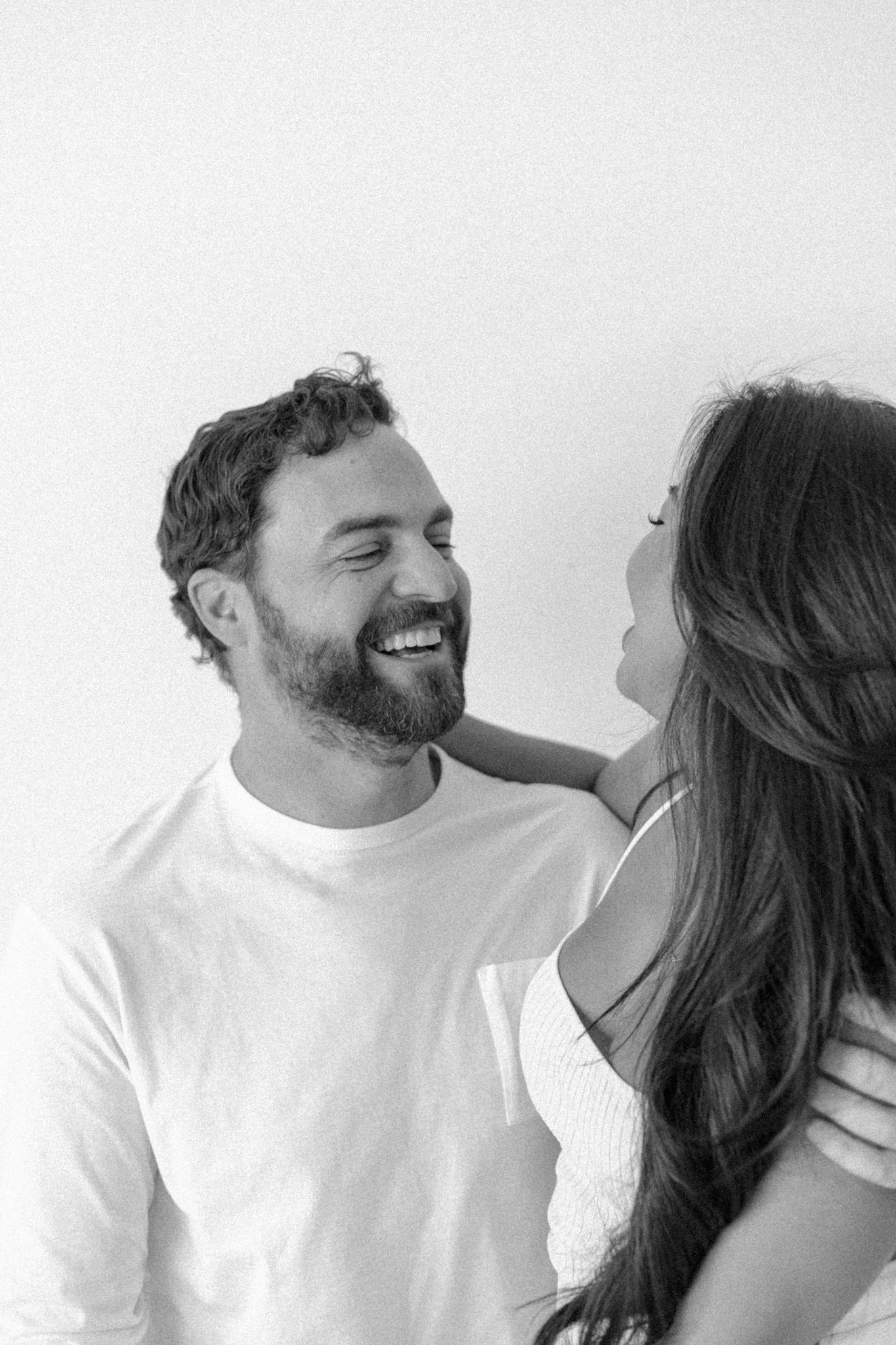 A joyful couple captured in a black and white studio portrait, highlighting love and connection.